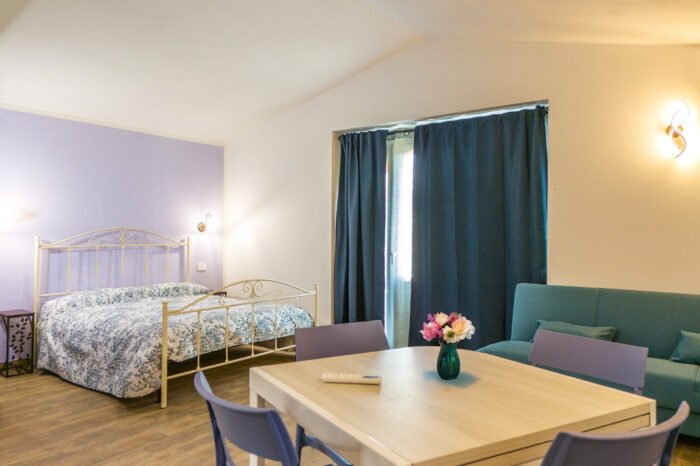 Letto matrimoniale e zona pranzo del Monolocale Familiare presso Podere Caneto