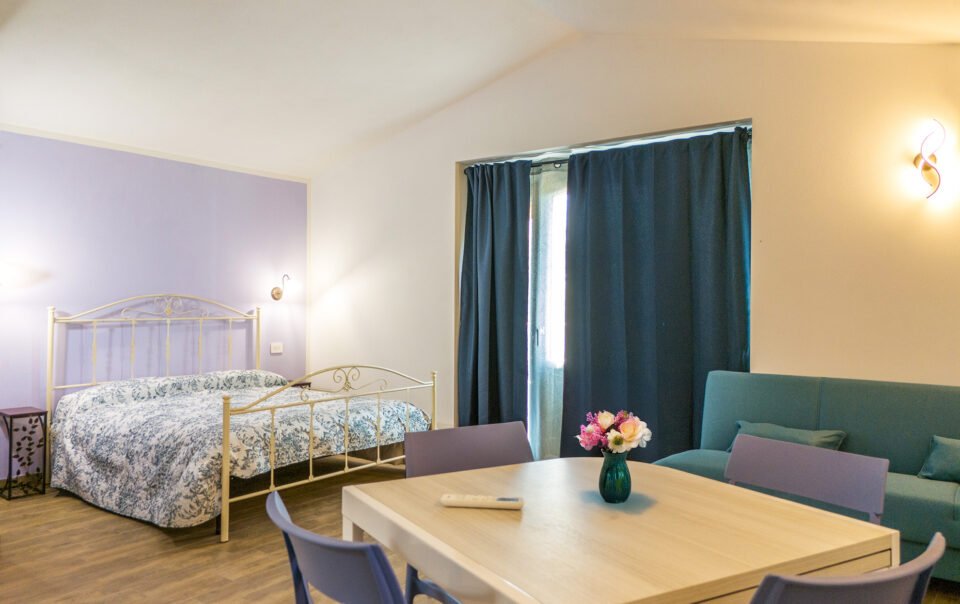 Letto matrimoniale e zona pranzo del Monolocale Familiare presso Podere Caneto